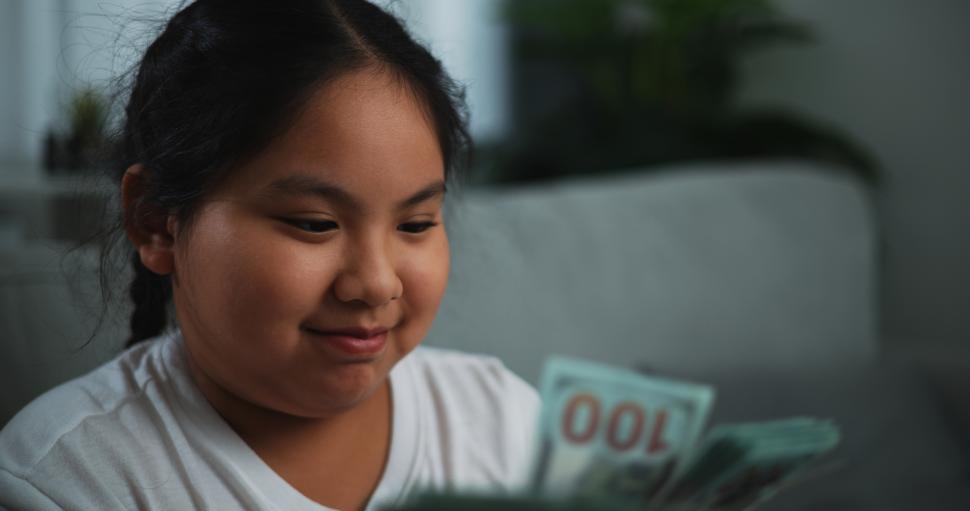 Free Image of Portrait of young Asian woman enjoy counting cash dollars banknotes on sofa in the living room at home. 
