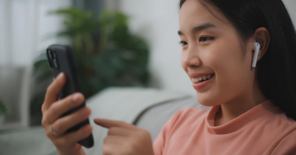 Free Image of Portrait young asian woman relax on comfortable couch at home shopping online on smartphone, smiling girl use cell phone chatting, browse wireless internet on gadget 