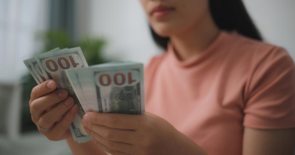 Free Image of Portrait of Happy young asian woman counts cash dollar bills while sitting in living room at home,counting stack cash money dollar 
