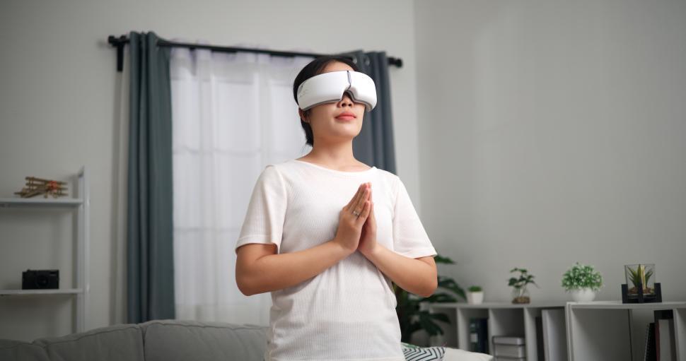 Free Image of Relaxed young woman wears VR goggles standing doing yoga  