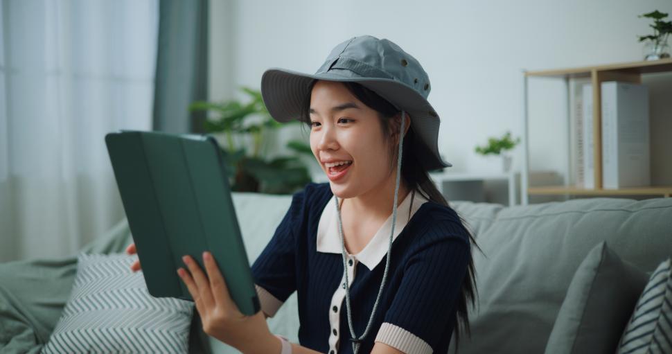 Free Image of Selective focus of Asian teenager woman sitting on sofa video call with friend while packing suitcase luggage for travelling, backpacker travel concept. 