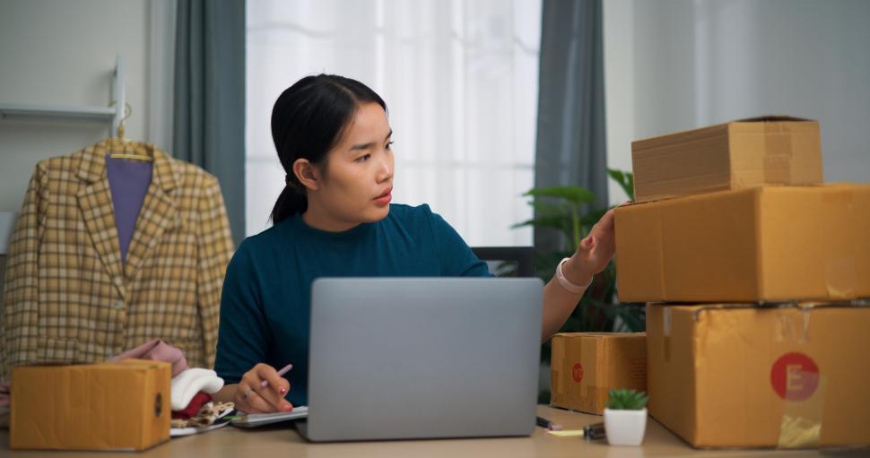 Free Image of Portrait of  Young asian woman business owner sitting at desk use laptop while check orders and write into book, Online Shopping 