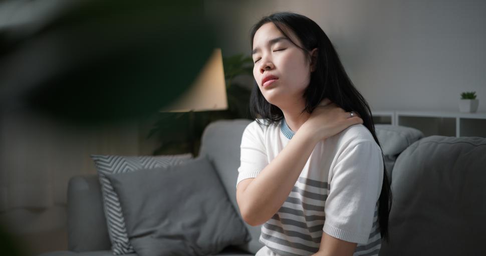Free Image of Portrait of Unwell young woman has neck pain while sitting on the sofa in the living room. People with muscle-body problems 
