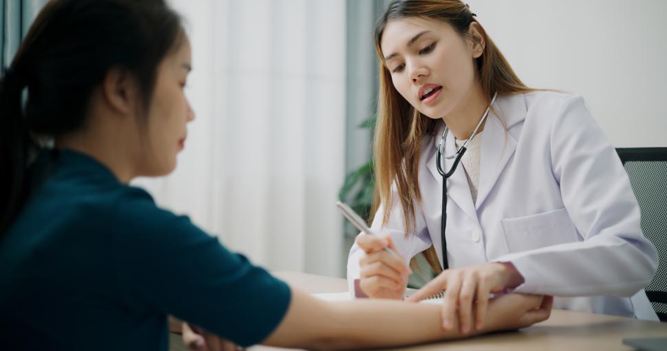 Free Image of Selective focus, Asian doctor examines sore arm of young female patient in clinic office, Health and medicine consultant, conversation about healthcare 