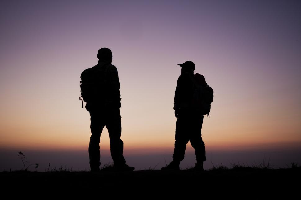 Free Image of Silhouette of Hiker men with backpack stay on cliff and think on the top mountain at sunset 