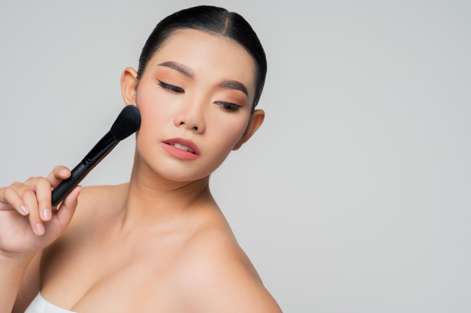 Free Image of Portrait of Beautiful Asian woman holding makeup blusher brush 