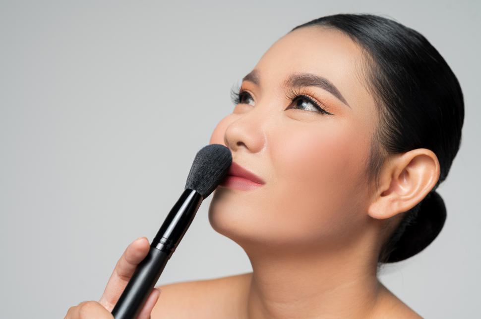 Free Image of Portrait of Beautiful Asian woman holding makeup blusher brush 