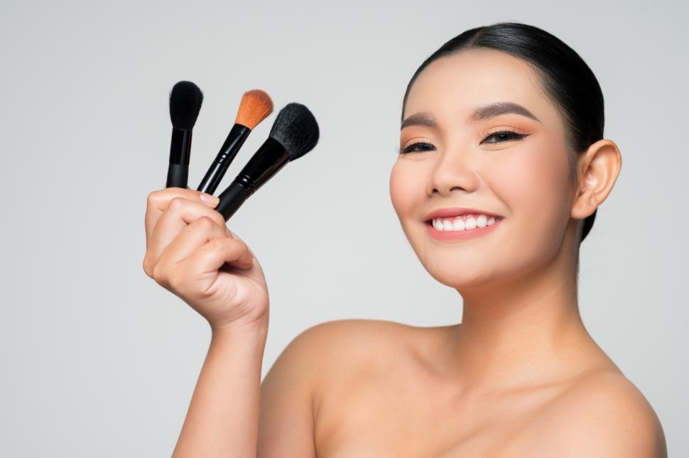 Free Image of Portrait of Beautiful Asian woman holding makeup blusher brush 