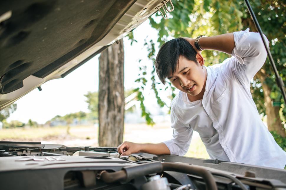 Free Image of Man opens the hood of a car to fix the car. 