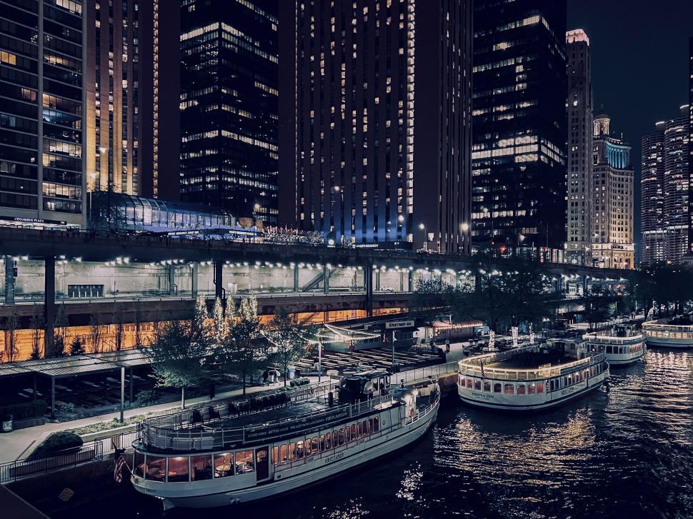 Free Image of Evening stroll along the Chicago Riverwalk with boats illuminated by city lights 