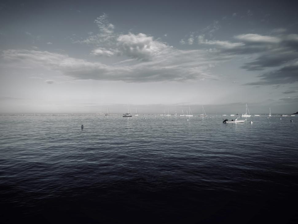 Free Image of Sailboats anchored on tranquil Lake Michigan with distant clouds in a serene coastal landscape during late afternoon 