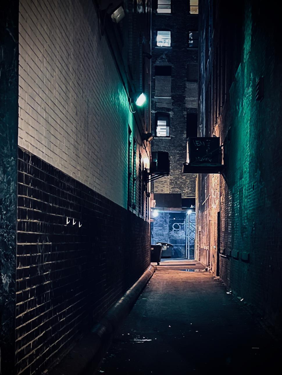 Free Image of Narrow Chicago alleyway illuminated by green and blue lights at night revealing mysterious surroundings 
