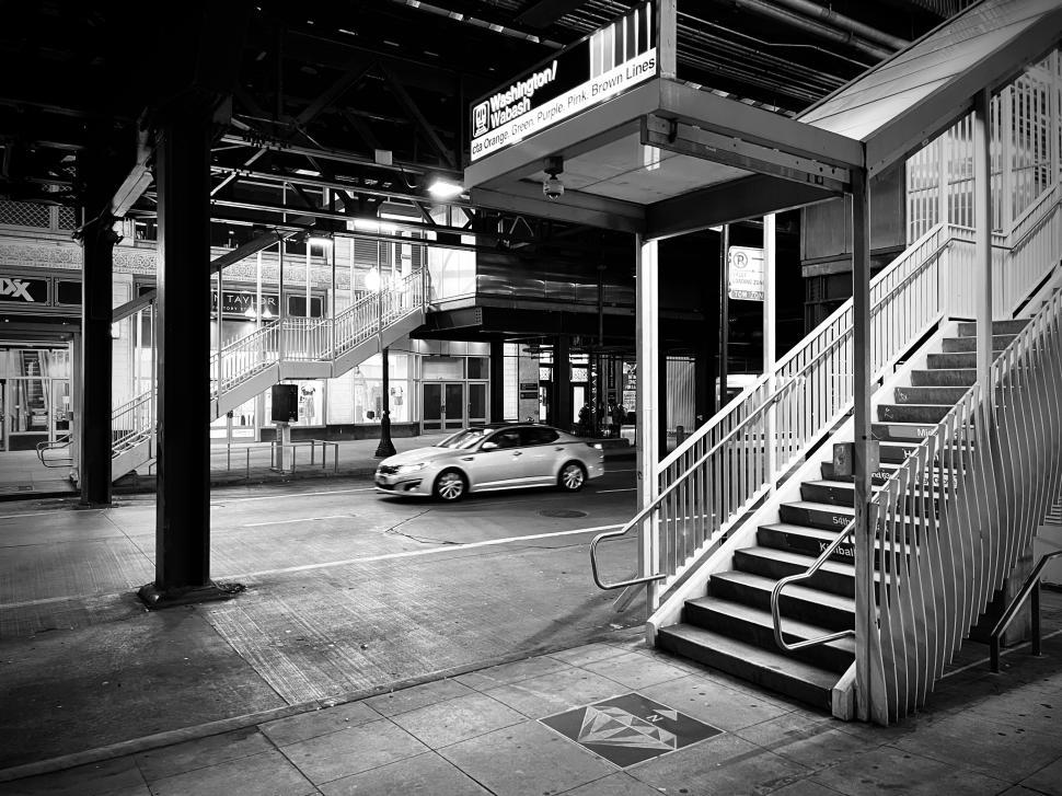 Free Image of Stairs leading to public transport area during a quiet urban evening in Chicago with passing cars 