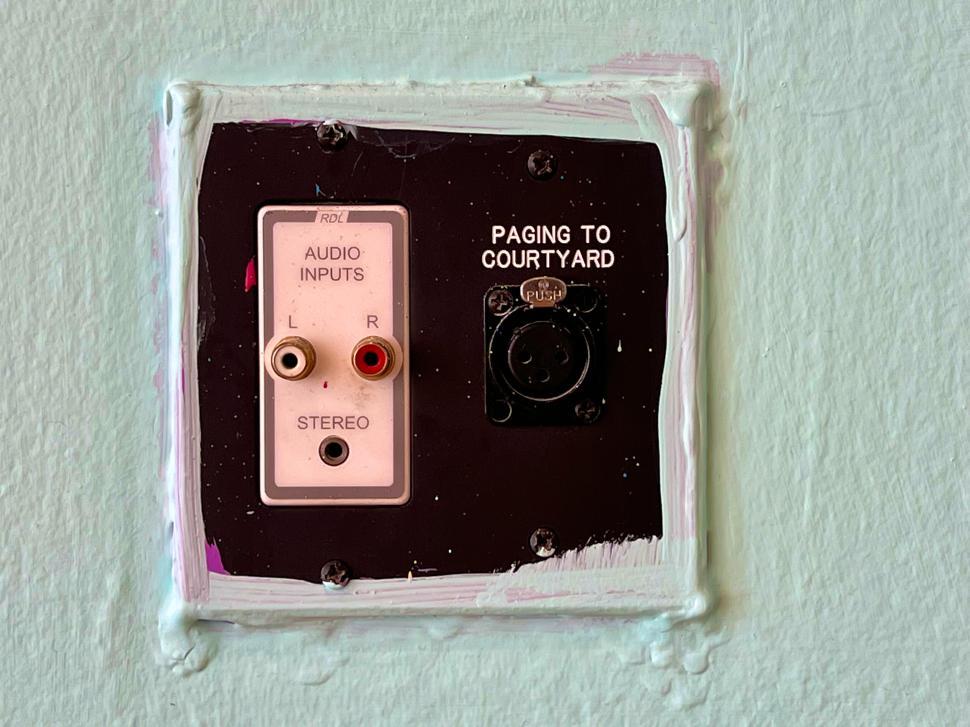 Free Image of Audio input and paging system installed on a mint green wall in a public space 