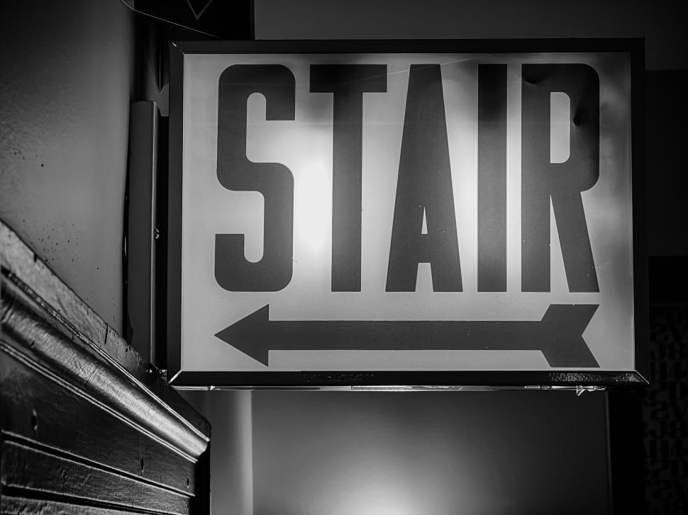 Free Image of Sign indicating direction to stairs in a dimly lit hallway 