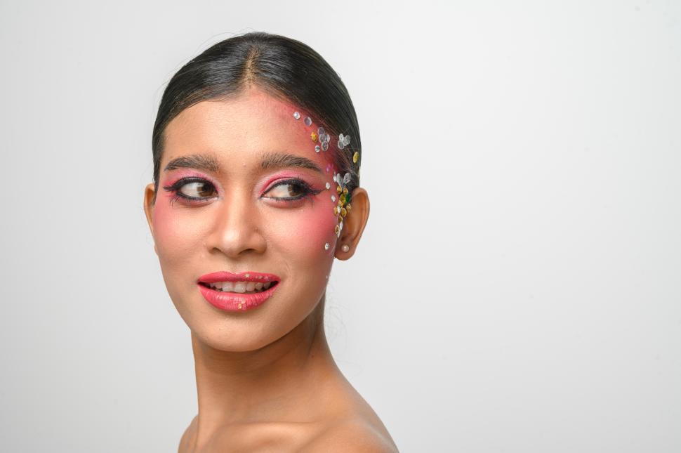 Free Image of Woman wearing pink makeup and embellishments on her face 