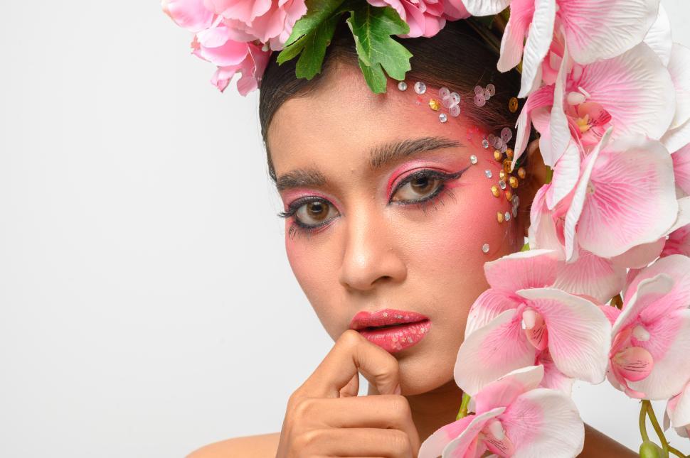 Free Image of The woman wore pink makeup and beautifully decorated the flowers. 