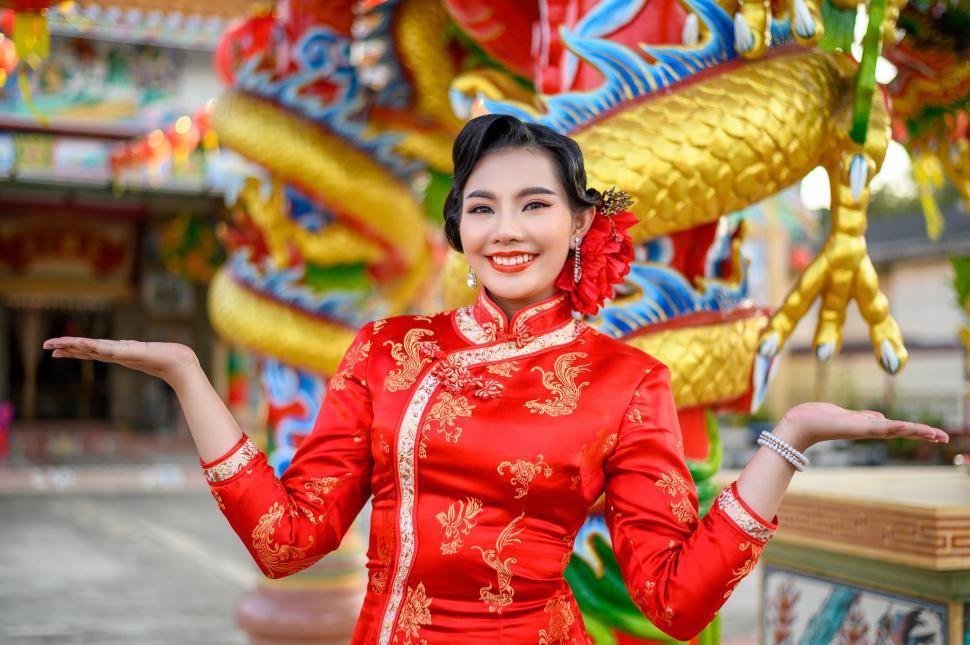 Free Image of Asian beautiful woman wearing a cheongsam poses at shrine on Chinese New Year 