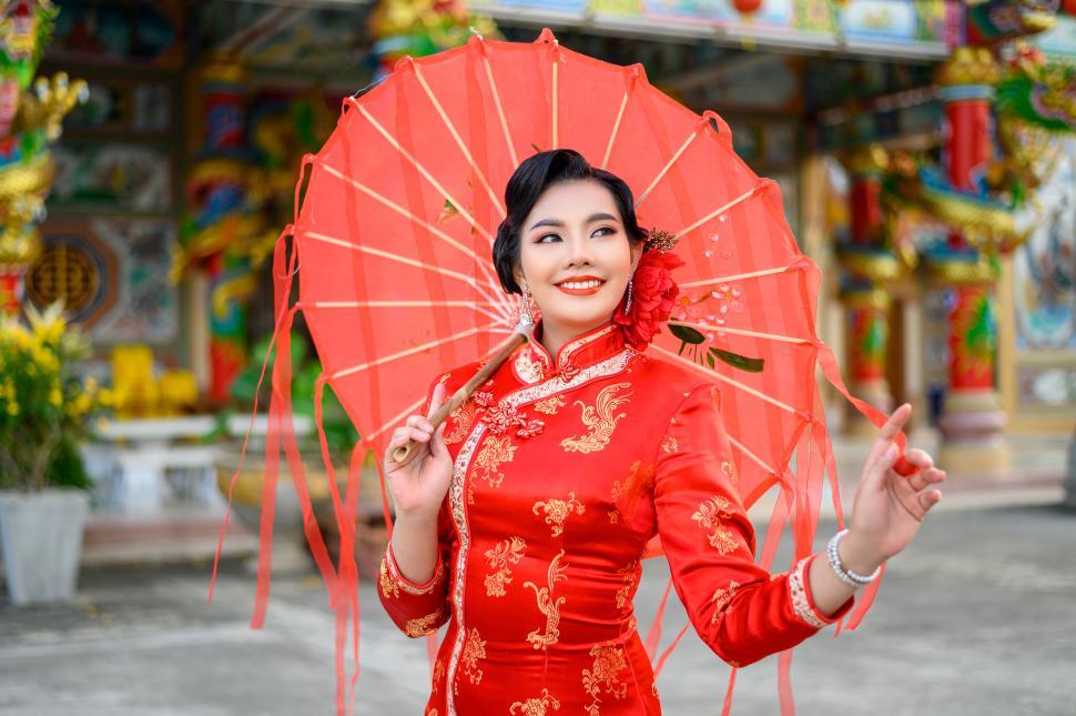Free Image of Asian beautiful woman wearing cheongsam with umbrella at shrine on Chinese New Year 