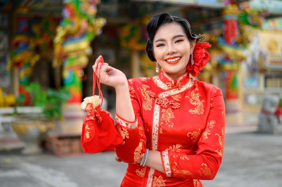 Free Image of Asian beautiful woman wearing a cheongsam show Red amulet bag at shrine on Chinese New Year 