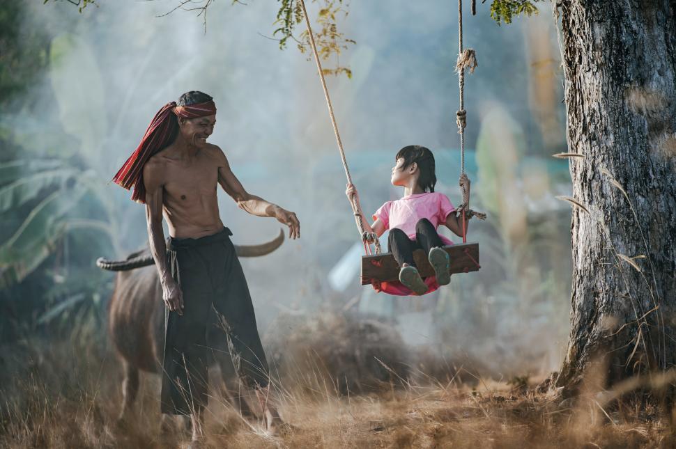 Free Image of Asian cute girl joyful swinging on rope wooden swing under tree 