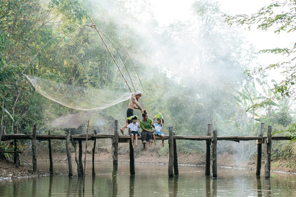 Free Image of Young mother playing with two daughters on wooden bridge 