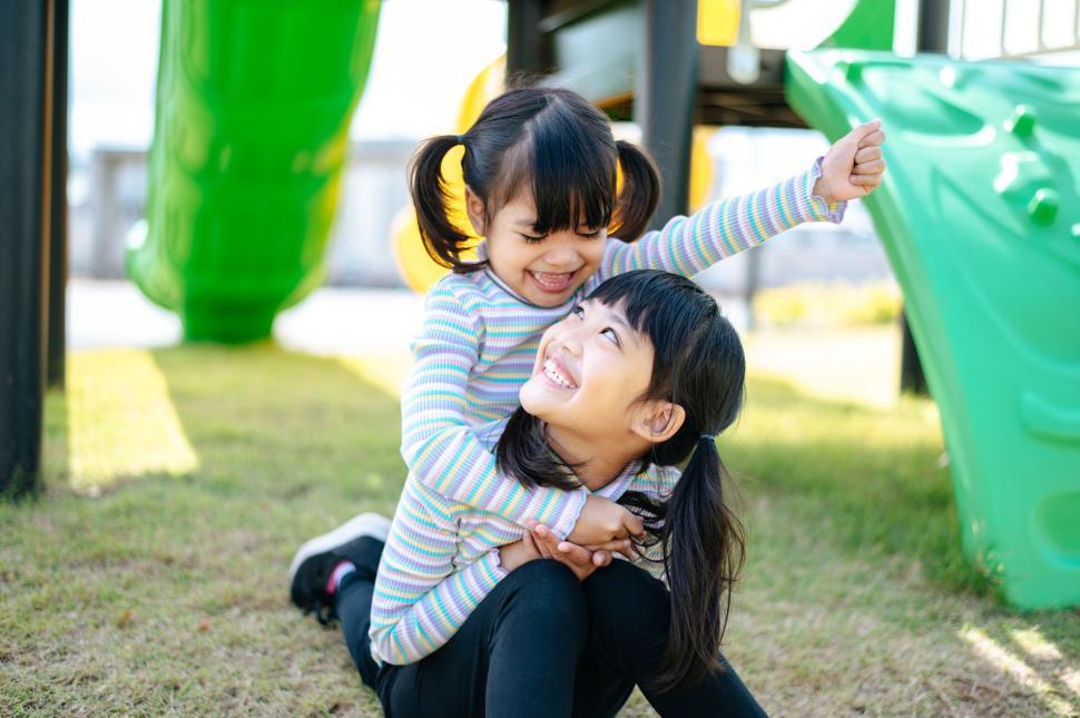 Free Image of Two girls riding each other on their backs in a playground. 