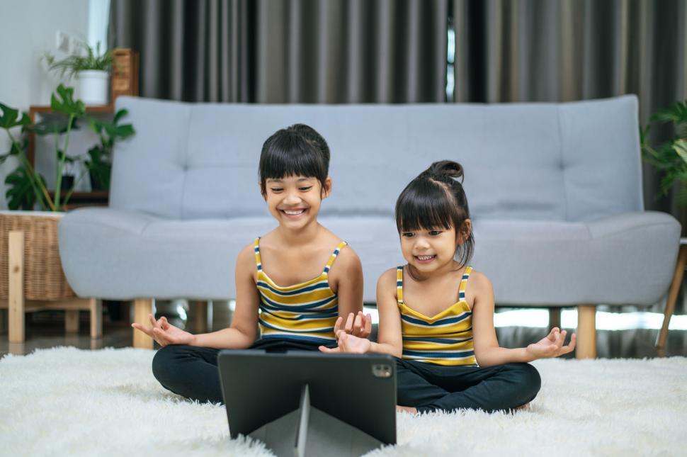Free Image of Two young women doing yoga in a room on a white carpet. 