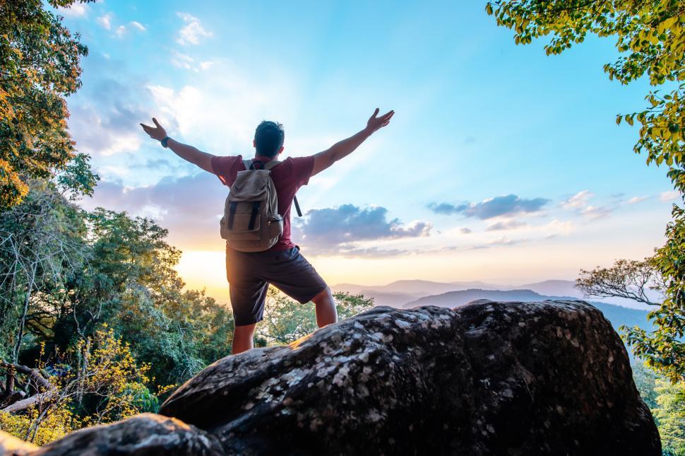 Free Image of Young trekking man standing on rocky mountain peak 
