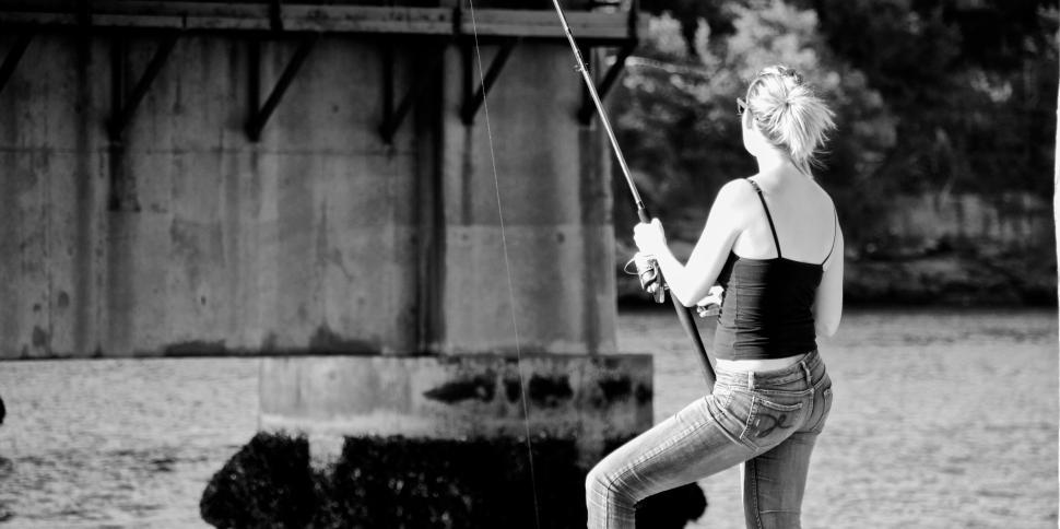 Free Image of Woman fishing near a bridge on a riverside afternoon 