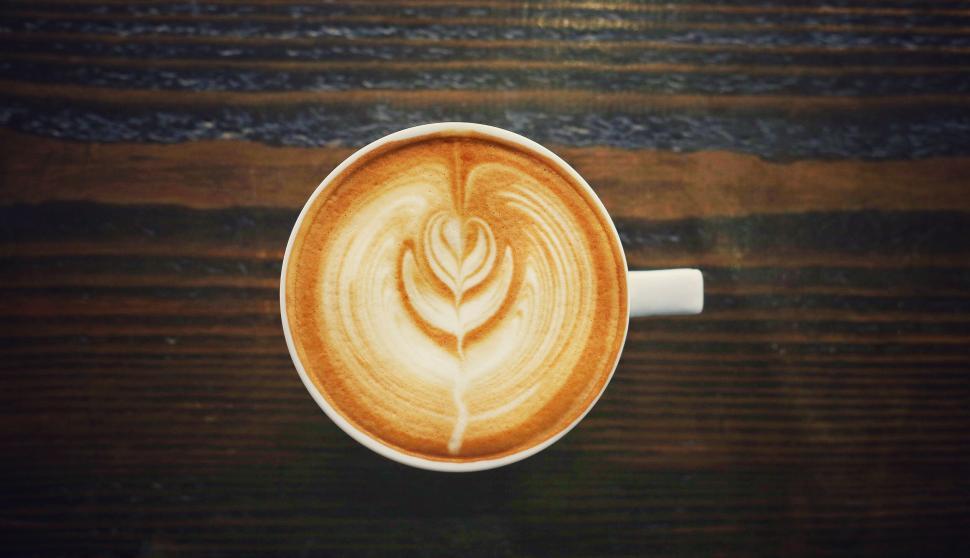 Free Image of Artistic latte coffee served on rustic wooden table top. 