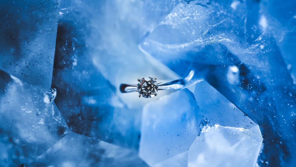 Free Image of Sparkling diamond ring on blue crystal rock surface. 