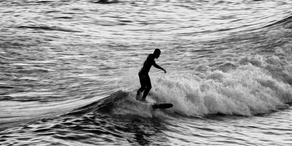 Free Image of Surfer riding a wave in a monochrome photograph 