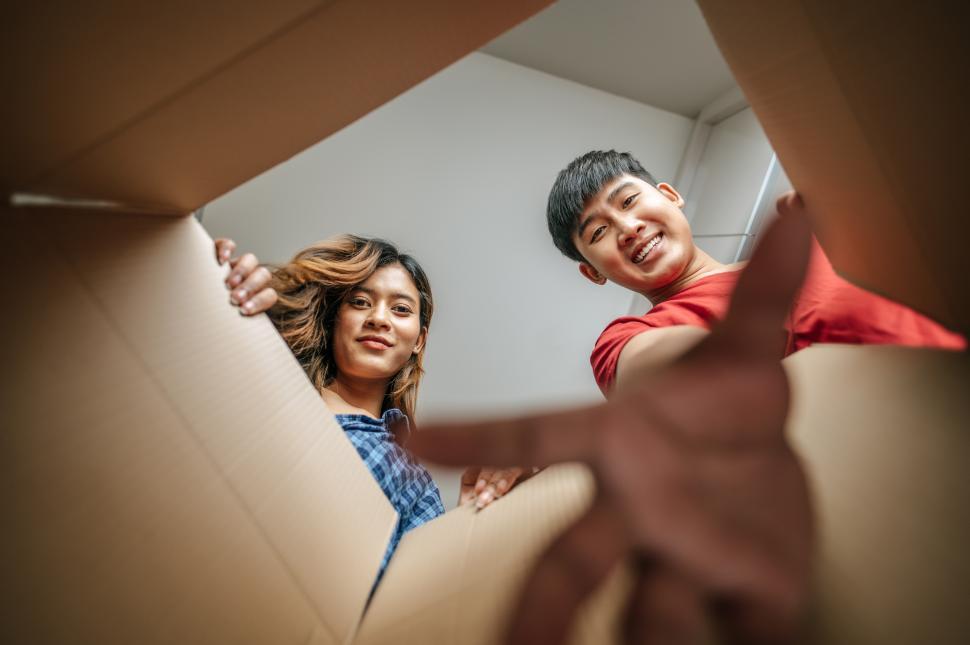Free Image of Young couple grabbing out of box Inside of package view 