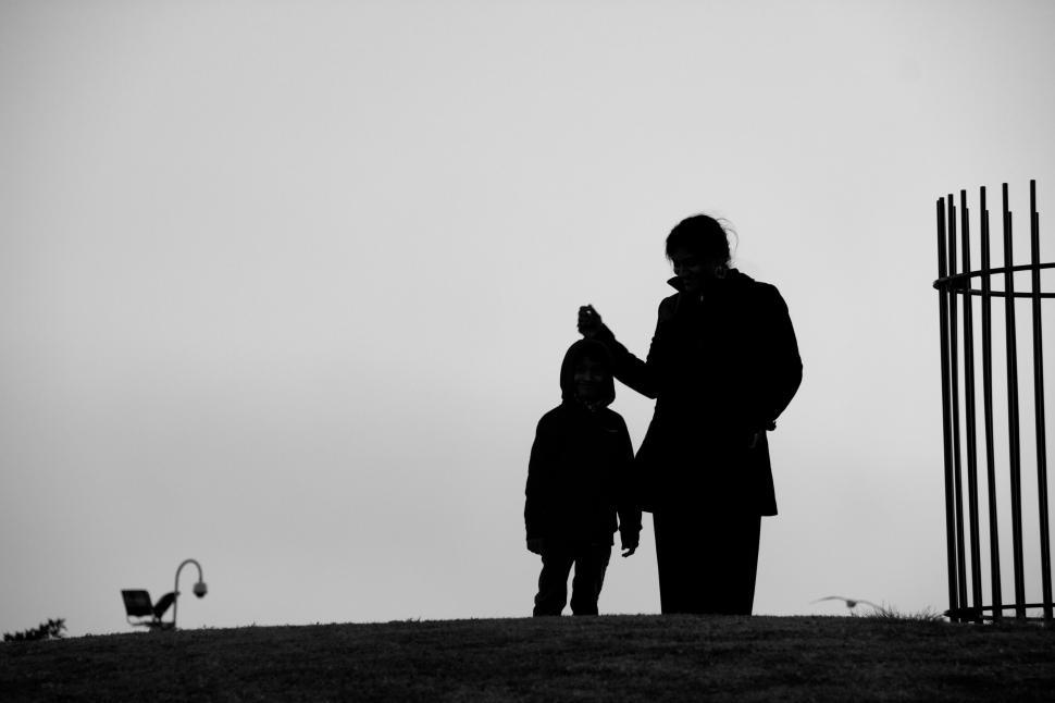 Free Image of Silhouette of adult and child holding hands on a hill 