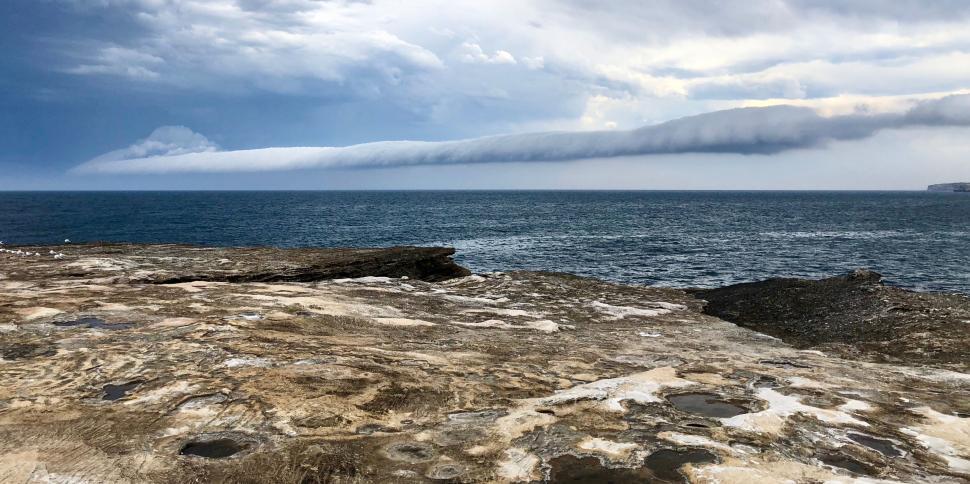 Free Image of Dramatic cloud formation over rocky coastal landscape. 