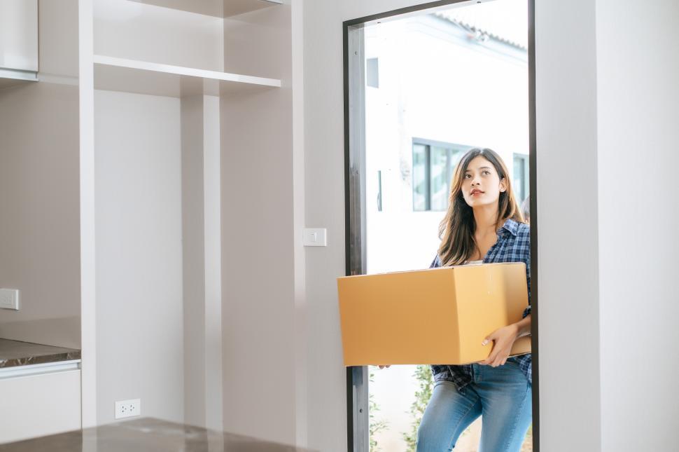 Free Image of Young woman carry large package walk into new house 