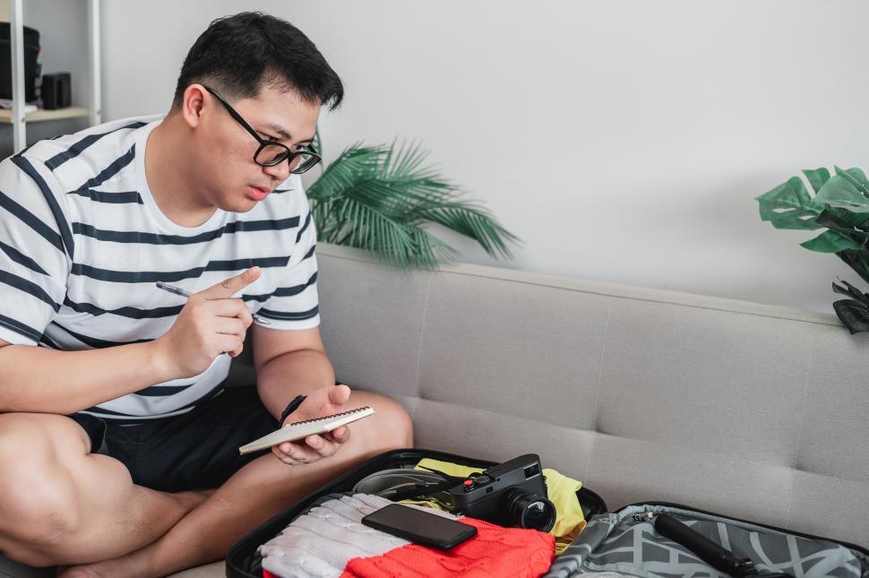 Free Image of Asian man is preparing clothes in suitcases 