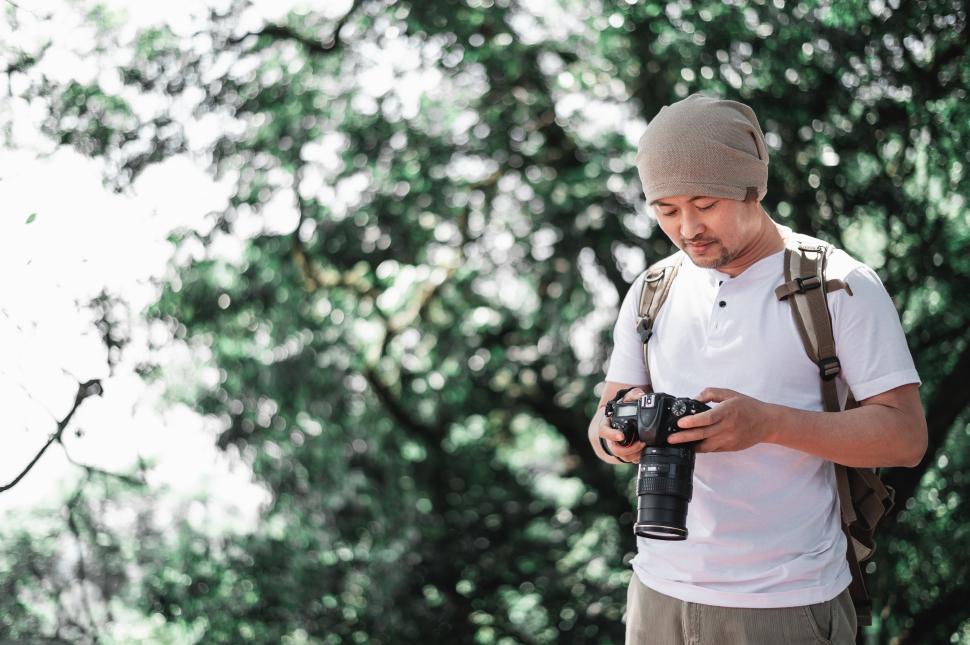 Free Image of Asian Traveler man checking a picture on camera at the park 