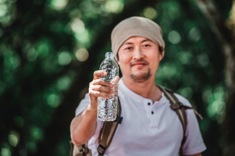 Free Image of Portrait Asian traveler man with backpack showing water bottle 