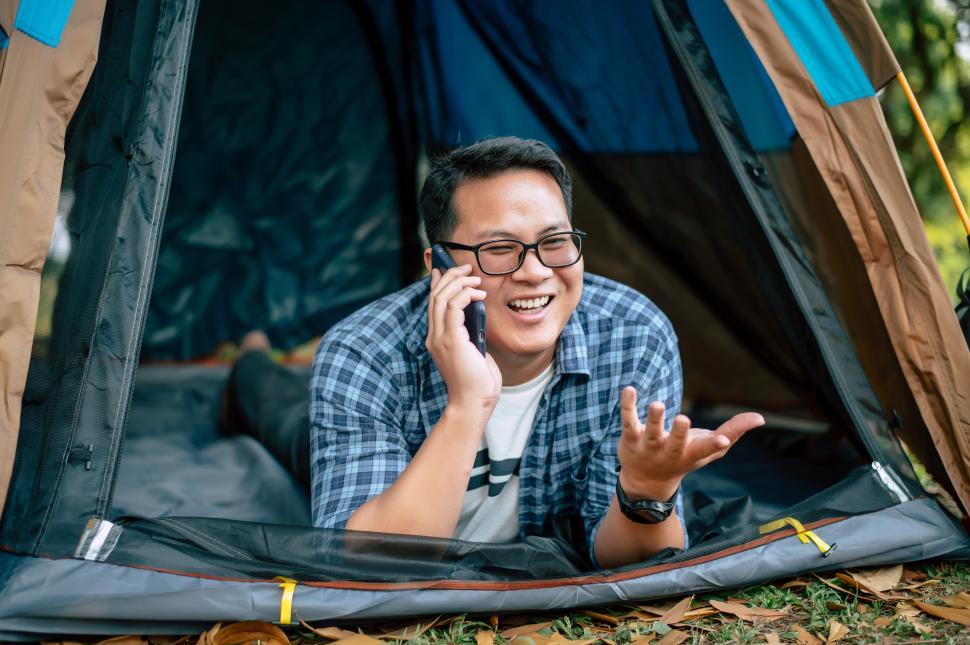 Free Image of Portrait of Happy Asian traveler man glasses lying in tent camping 