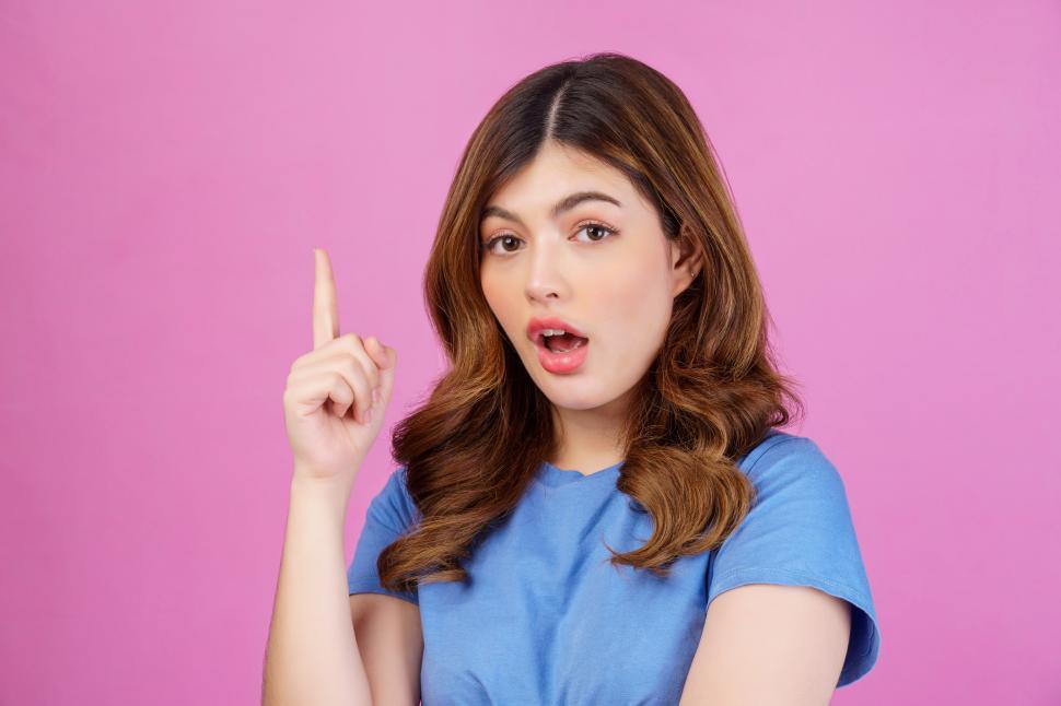 Free Image of Portrait of excited young woman wearing casual t-shirt thinking and imagination isolated over pink background 