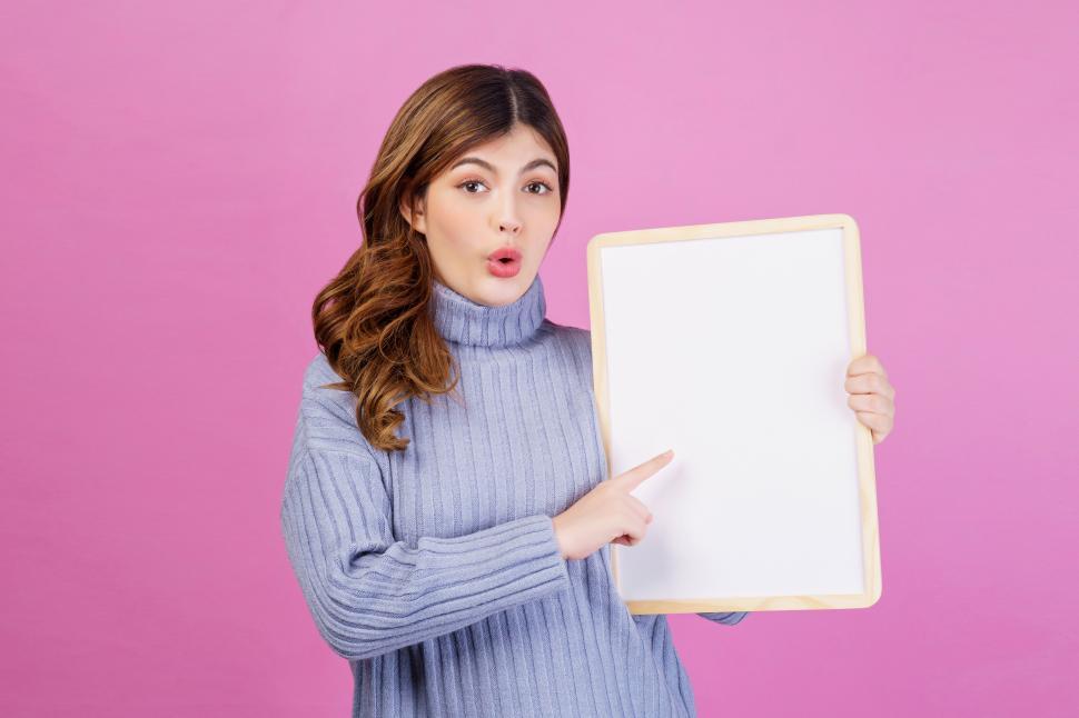 Free Image of Portrait of Happy young woman holding an empty white placard over isolated pink background. 