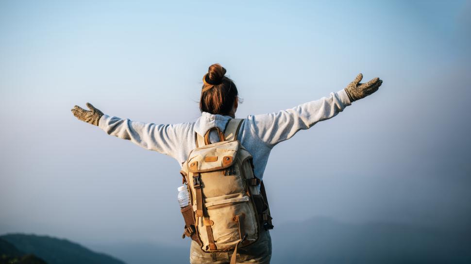 Free Image of Portrait of cheering hiking woman open arms to the sunrise stand on mountain 