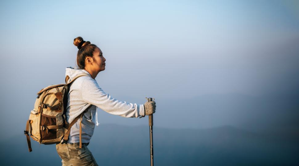 Free Image of Portrait of Asian young tourist woman is hiking on the top of the mounting and looking at a beautiful landscape with copy space 
