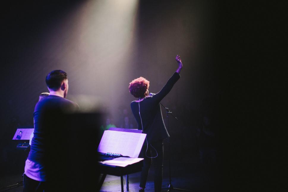 Free Image of Singer performing with musicians under stage spotlight. 