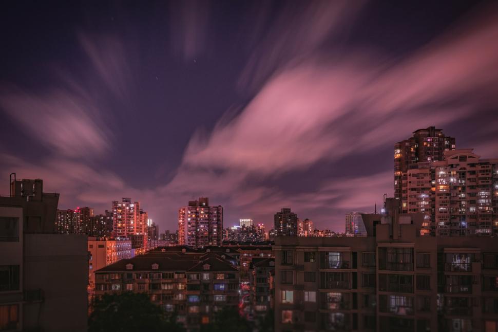 Free Image of Nighttime cityscape with buildings illuminated and sky 