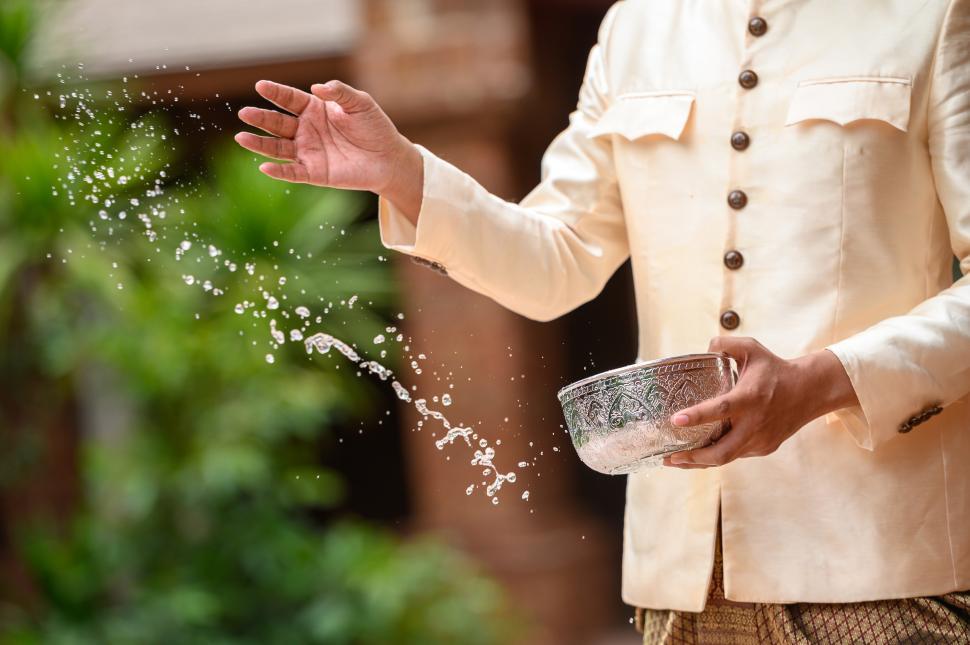Free Image of Young man splashing water from bowl on Songkran festival 