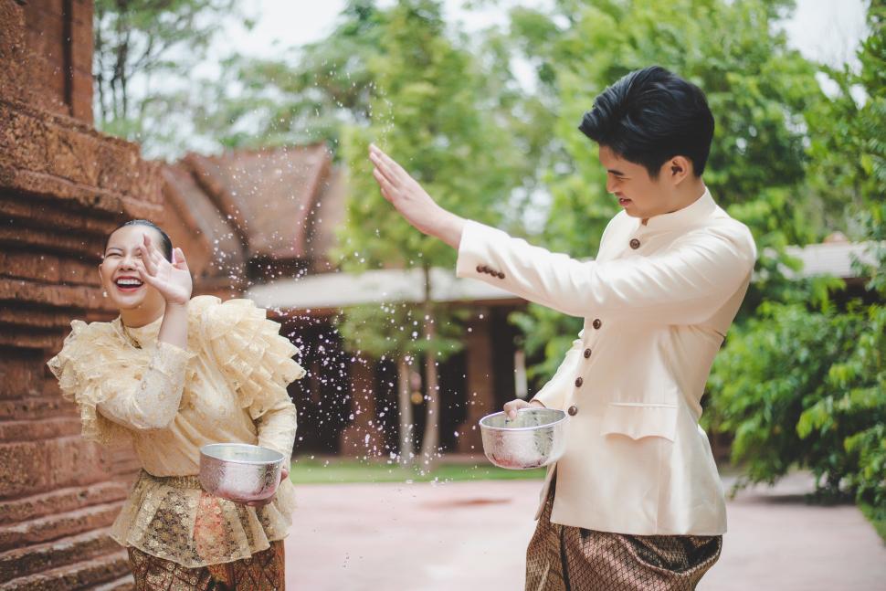 Free Image of Young couple splashing water from bowl on Songkran festival 