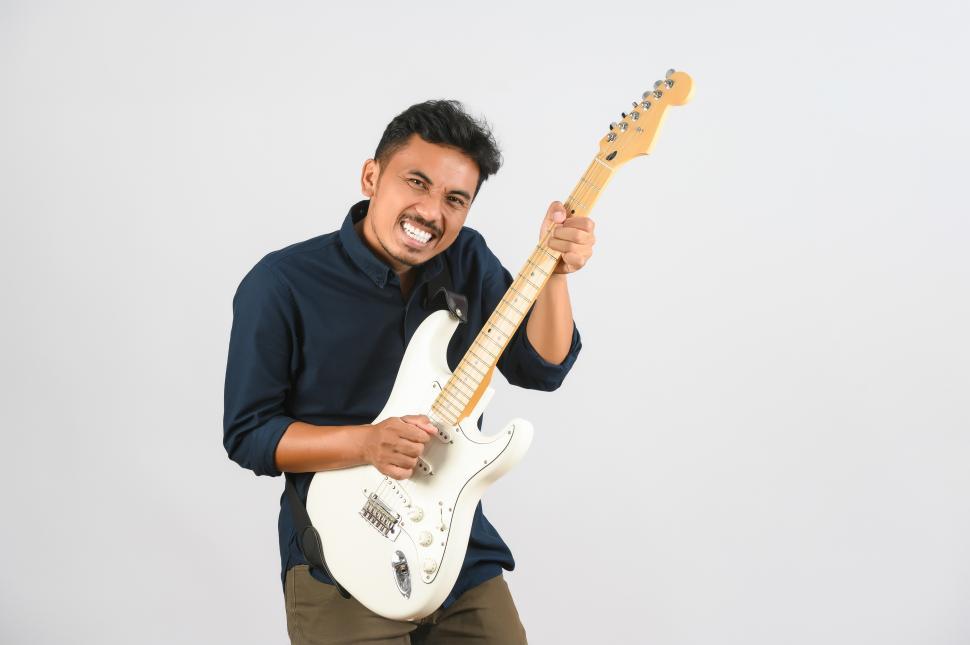 Free Image of Portrait of Young Asian man in blue shirt with electronic guitar isolated on white background 